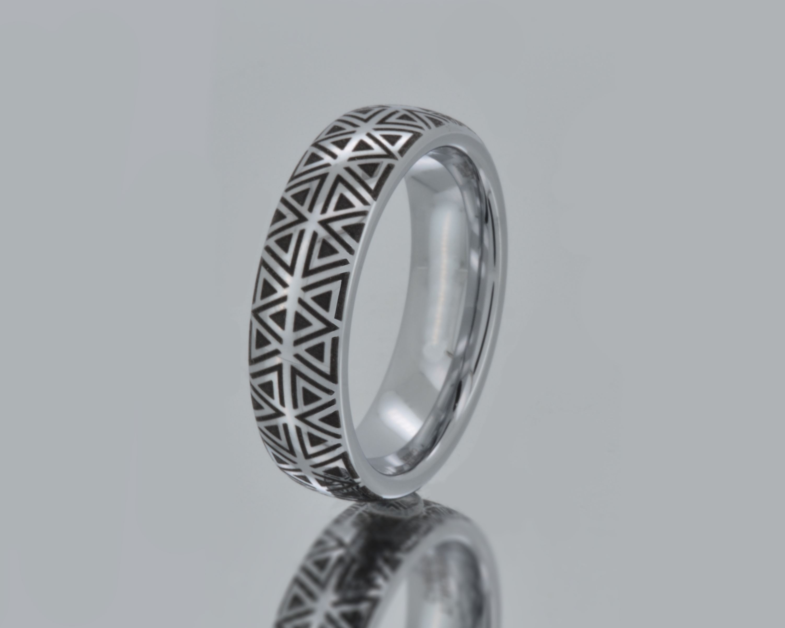 Silver ring with geometric pattern on a gray background