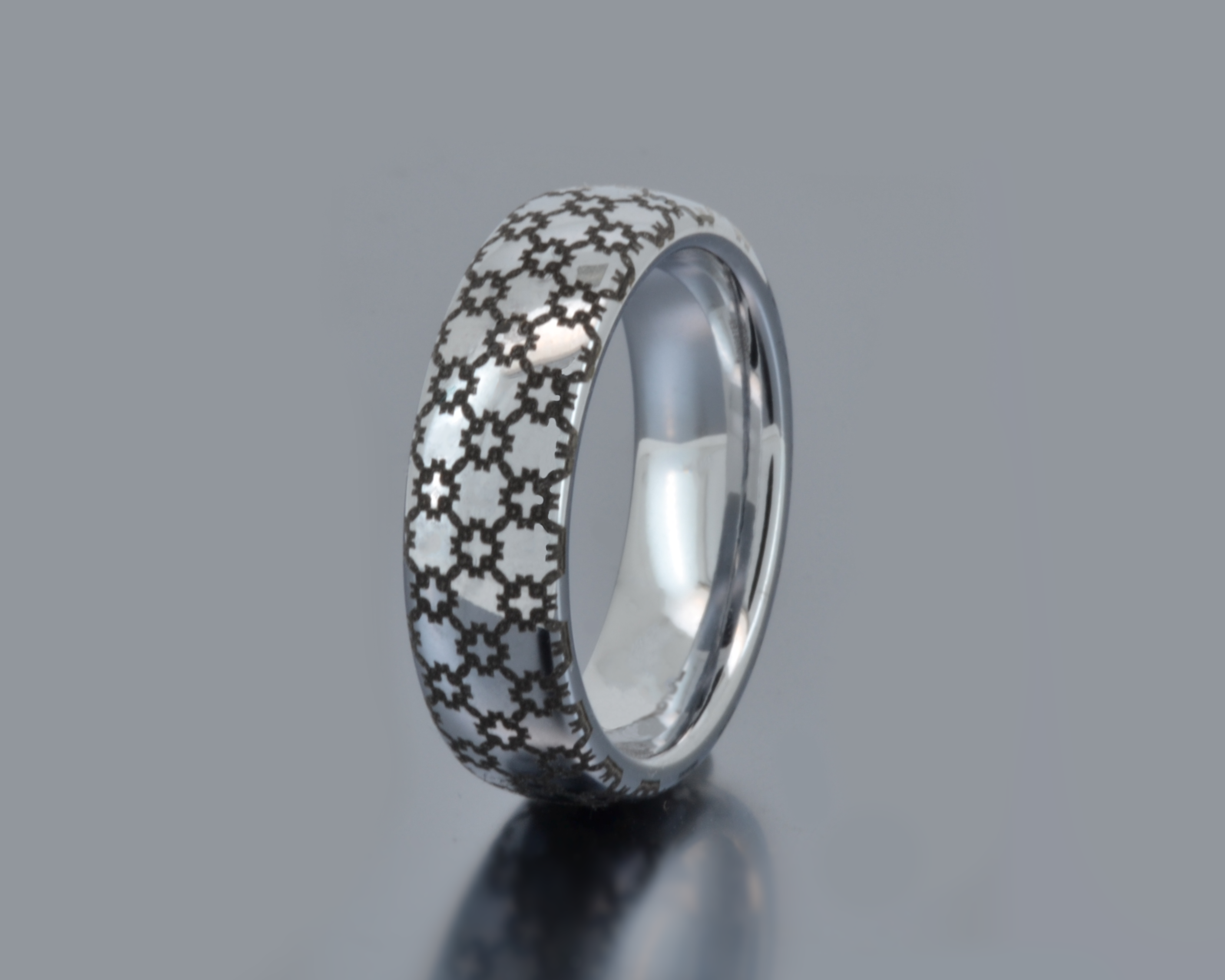 Silver ring with a patterned band on a gray background