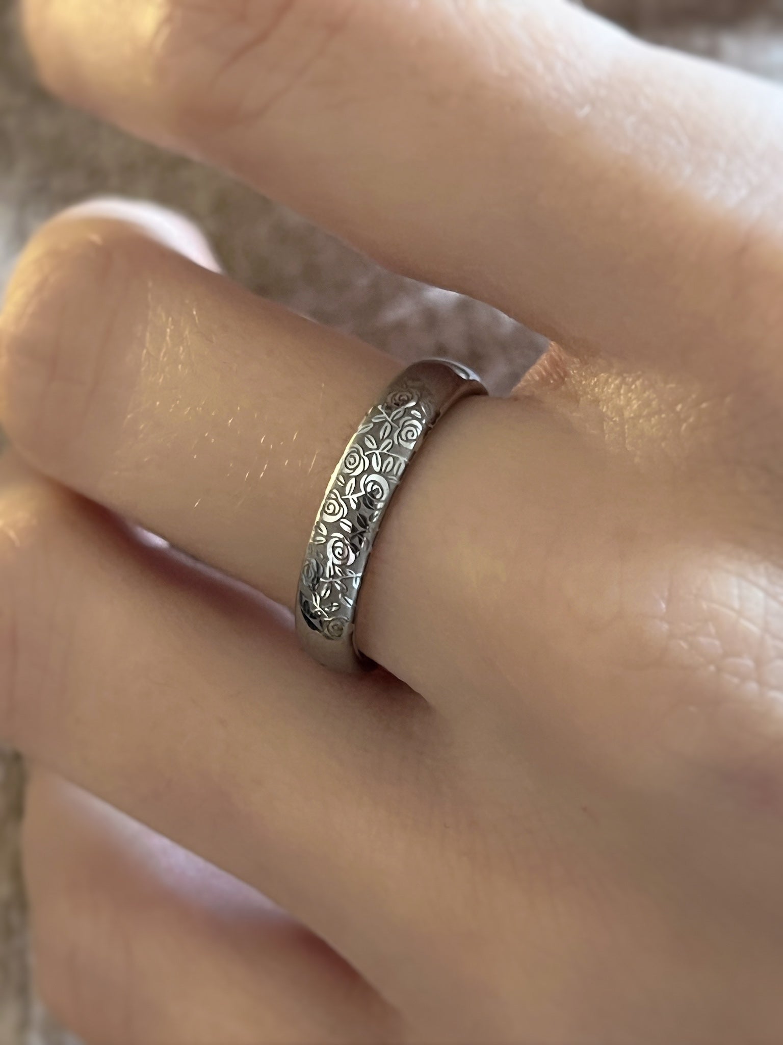 Close-up of Silver Blooming Rose tungsten ring worn on a finger, showcasing the detailed rose engravings.