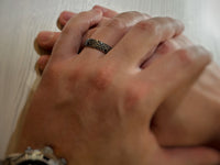 The Labyrinthine Loop tungsten ring with laser-engraved surface detail, worn on a hand.
