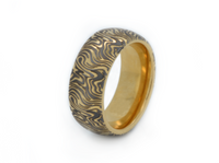 Golden Mokume Majesty tungsten ring with laser-engraved surface detail, shown against a light background.