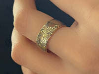 Golden Mokume Majesty tungsten ring with laser-engraved surface detail, worn on a hand.