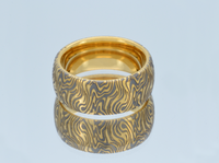 Product photo of the Golden Mokume Majesty tungsten ring with laser-engraved surface detail.