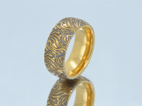Product photo of the Golden Mokume Majesty tungsten ring with laser-engraved surface detail.
