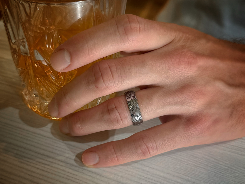 The Arrow Waves tungsten ring with laser-engraved surface detail, worn on a hand.