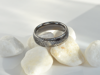 Product photo of the The Arrow Waves tungsten ring with laser-engraved surface detail.