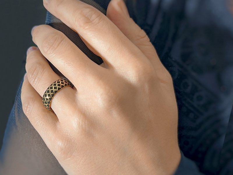 Golden Black Quilted Elegance tungsten ring with laser-engraved surface detail, worn on a hand.