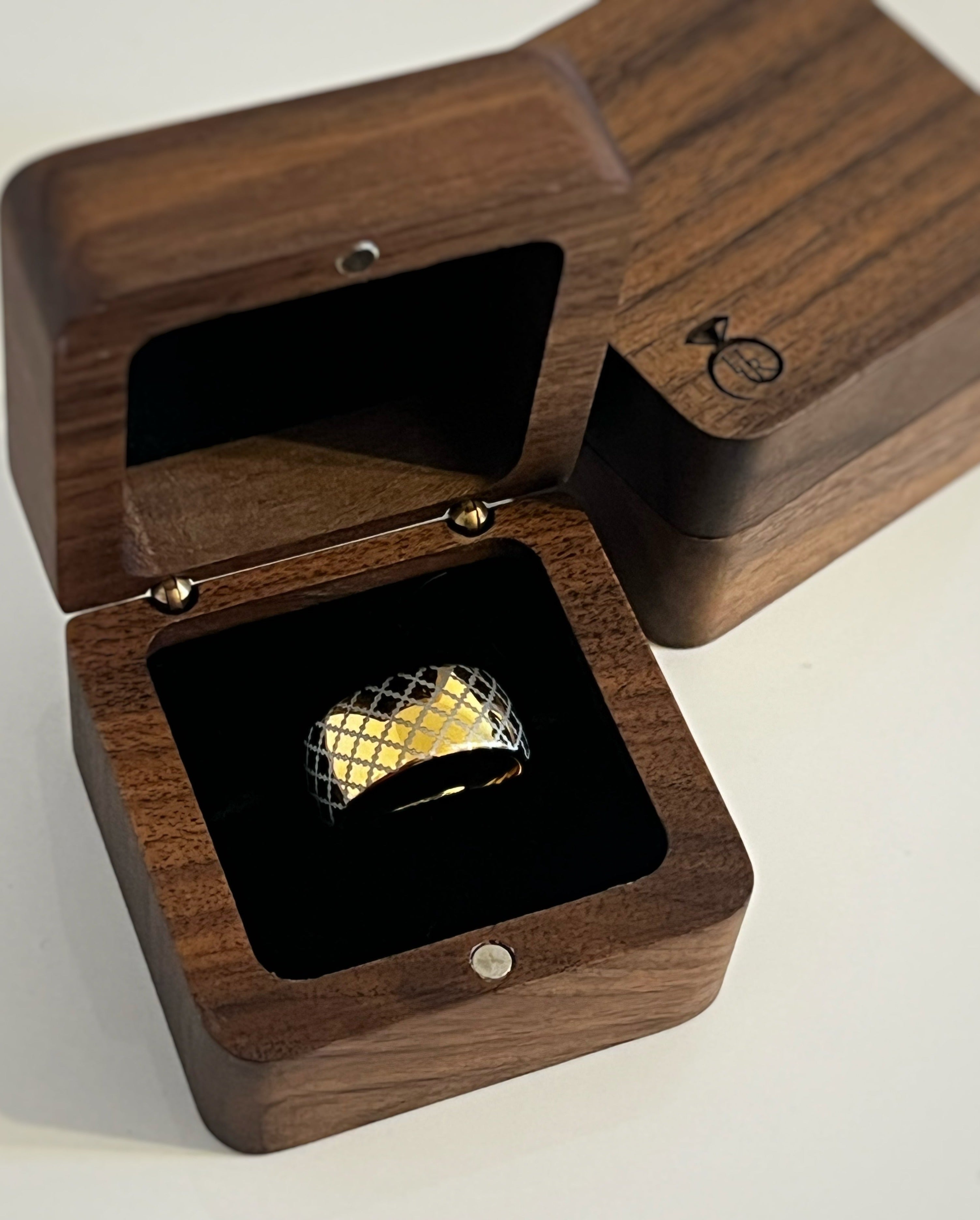 Gold tungsten ring with a quilted pattern, displayed in an open wooden ring box with a black interior.