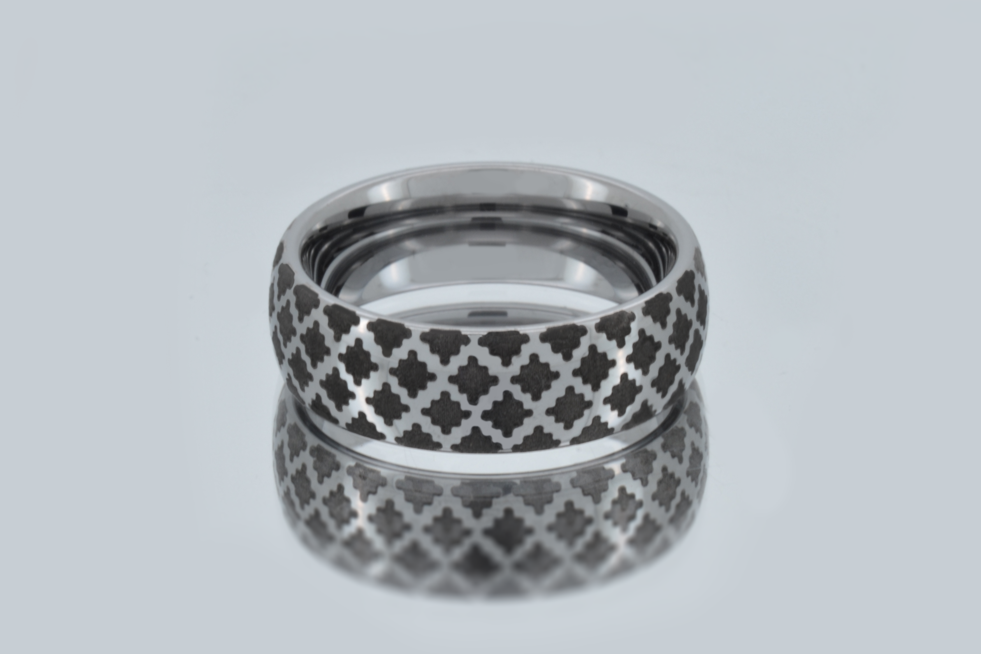 Tungsten ring with a white gold-plated surface and a timeless diamond pattern displayed on a mirror