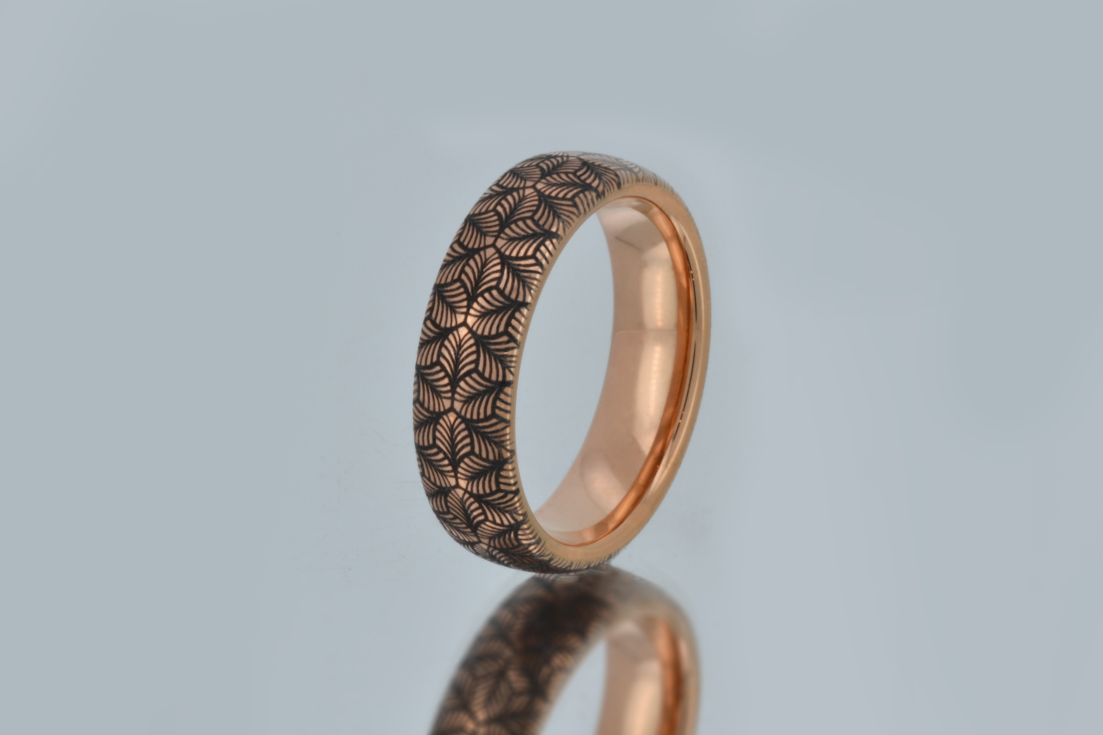 Rose gold tungsten ring with an intricate, black-engraved petal-like pattern, on amirror offering a delicate and refined look, perfect for weddings, special occasions, or everyday wear.