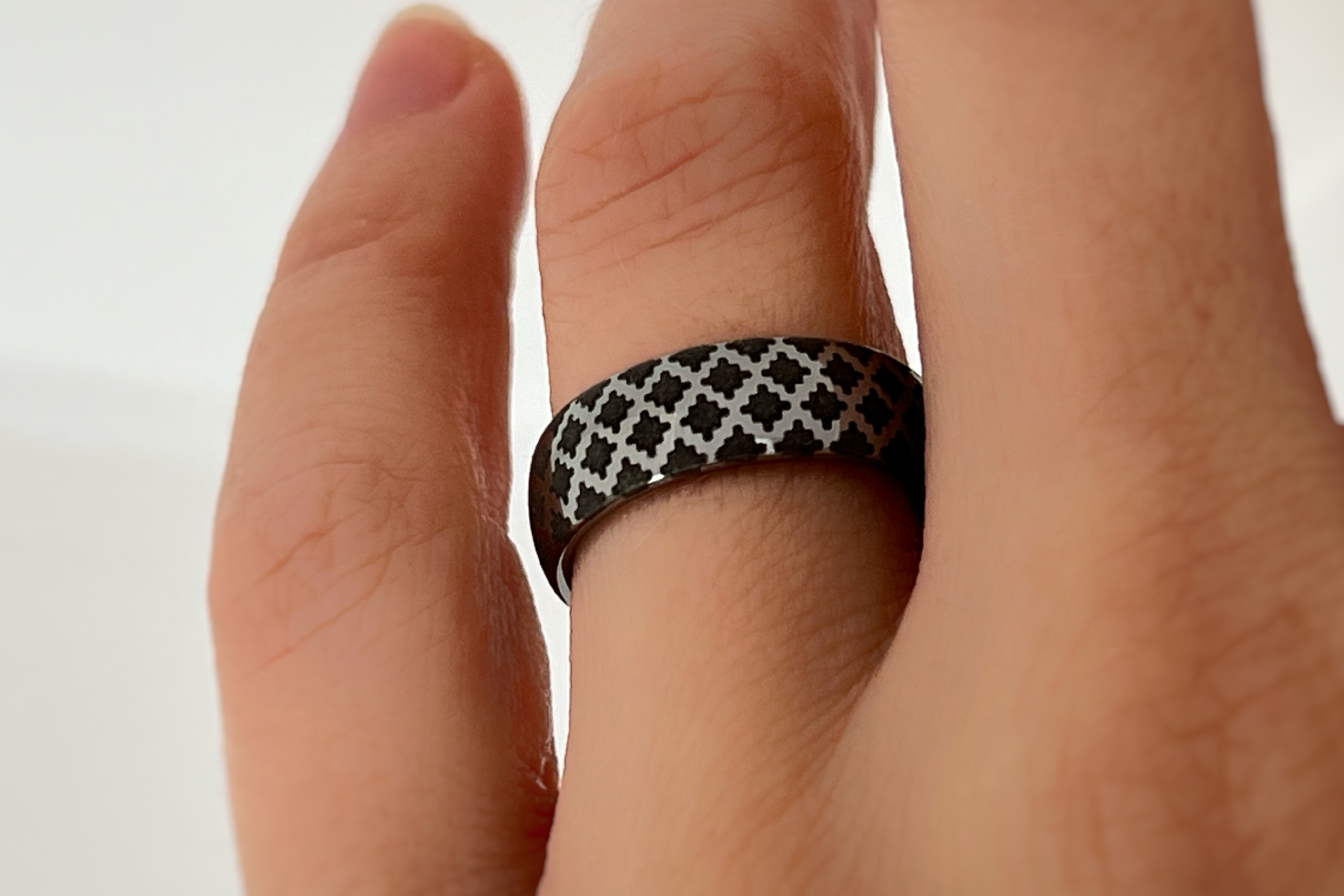 White gold tungsten ring with black engraved quilted pattern worn on hand