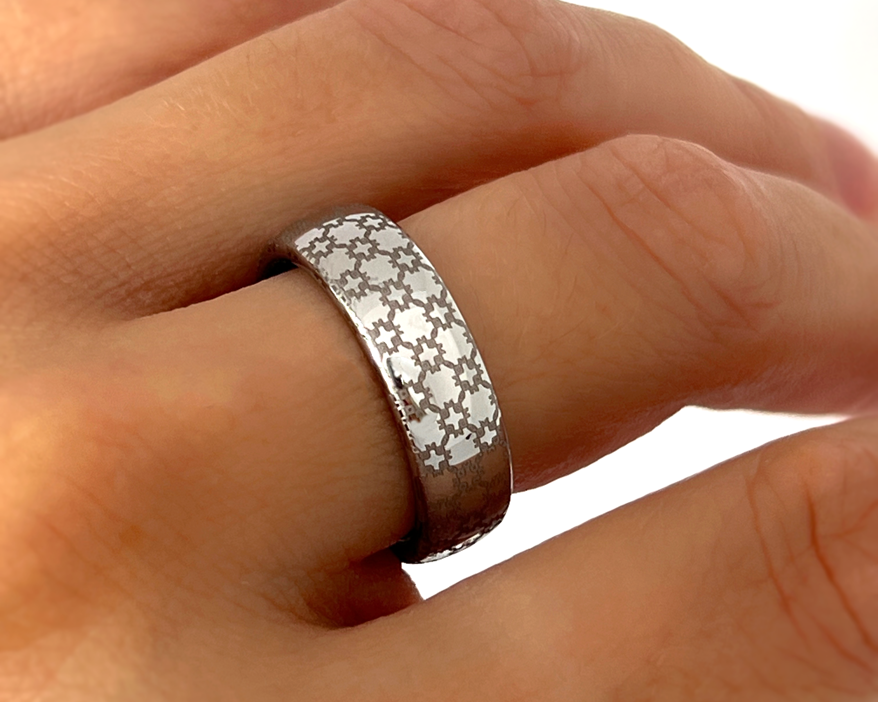 Close-up of a hand wearing a silver ring with star patterns on a white background