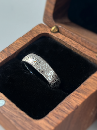 Product photo of the Floral Reverie tungsten ring with laser-engraved surface detail.