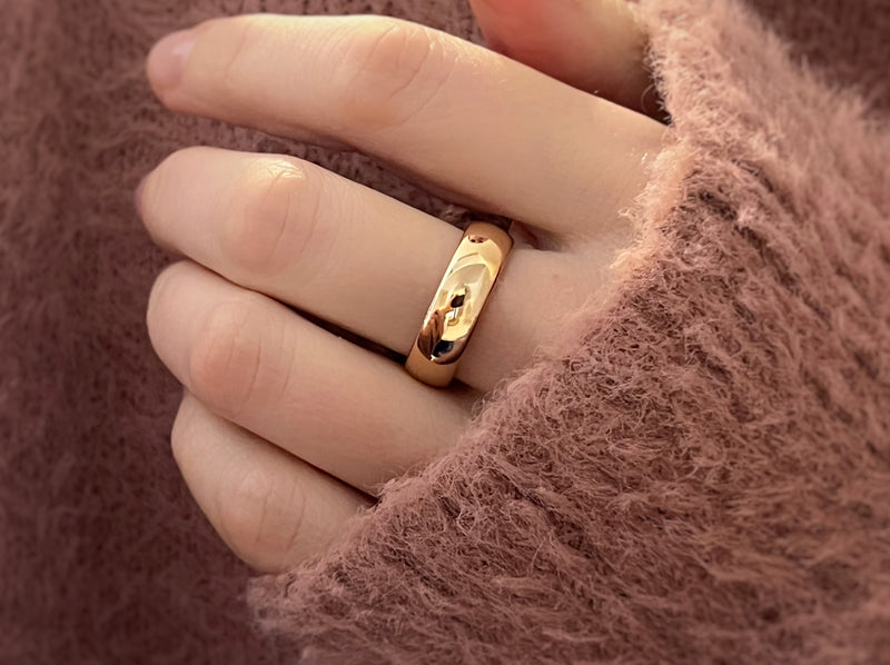 minimalist luxury rose gold plated tungsten ring, mirror polished, shiny anniversary wedding band on a hand of a model