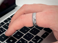 Eternal Knot tungsten ring with laser-engraved surface detail, worn on a hand.