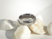 Product photo of the The Arrow Waves tungsten ring with laser-engraved surface detail.