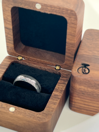 Product photo of the Serpente Eterno Black tungsten ring with laser-engraved surface detail.