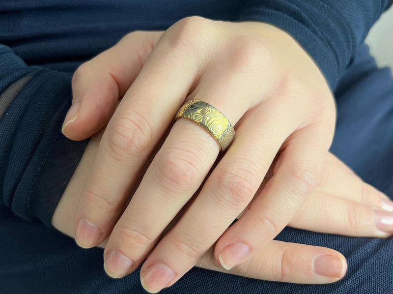 unique mokume ganne damascus pattern on yellow gold plated tungsten ring, elegant luxury wedding band for special occasions, anniversary engagement gift for her and him on a model hand