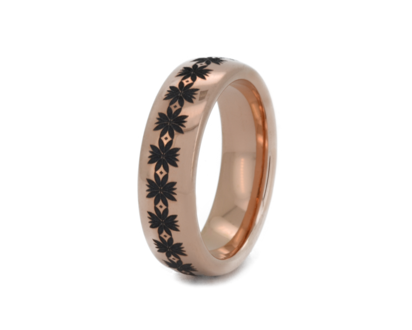 Rose gold ring with black floral engraving on a white background