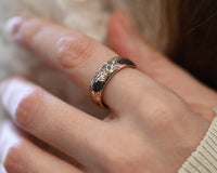 Close-up of a rose gold tungsten ring worn on hand, featuring intricate oak leaf engraving and polished finish. Unique botanical wedding band inspired by nature.