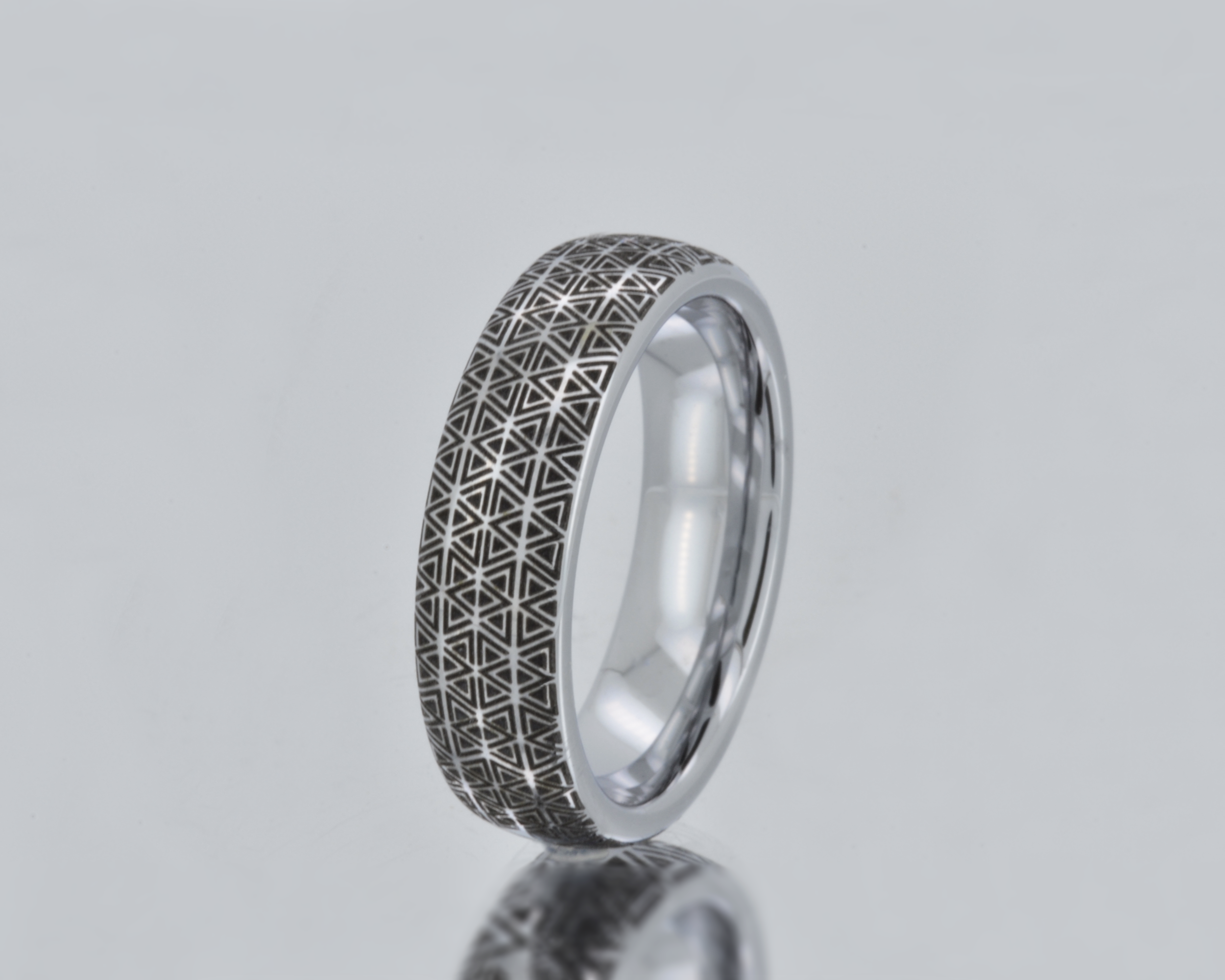 Silver ring with geometric pattern on a gray background