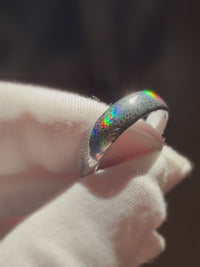 Baroque Radiance tungsten ring held in a white glove, with holographic baroque details reflecting spectral colors.