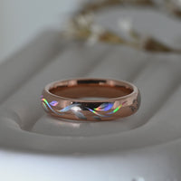 Video of a rose-gold Botanic Glow tungsten ring on a pale display surface, showing flowing holographic leaf-inspired lines.