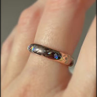 Video of a rose-gold Sakura Glow tungsten ring worn on a finger, showing holographic sakura blossoms and leaves.