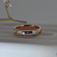 Video of a rose-gold Lotos Glow tungsten ring on a pale display surface, showing a holographic lotus flower and flowing leaves.