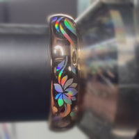 Close-up video of a Lotos Glow ring on a metal holder, showing rainbow reflections across its lotus motif and leaves.