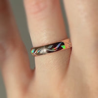 Video of a rose-gold Botanic Glow ring worn on a finger, with colorful organic lines shifting in the light.