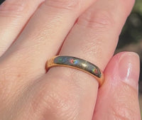 Holographic tungsten ring worn on hand, featuring a delicate heart and floral pattern with colorful rainbow reflections. Romantic wedding band with a polished gold finish.