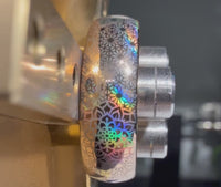 Close-up video of the Boho Holo Mandala tungsten ring during the engraving process, showing a mandala-inspired pattern with holographic rainbow reflections under the light.