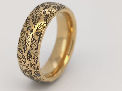 Elegant gold ring with intricate oak leaf engraving. This tungsten ring features a detailed oak leaf pattern that symbolizes strength and endurance. Perfect as a unique wedding band or stylish everyday accessory. High-quality craftsmanship combined with the durability of tungsten and the timeless appeal of gold.