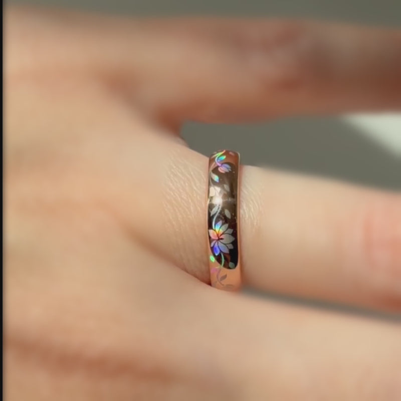 Video of a rose-gold Lotos Glow ring worn on a finger, with colorful lotus petals shifting in the light.